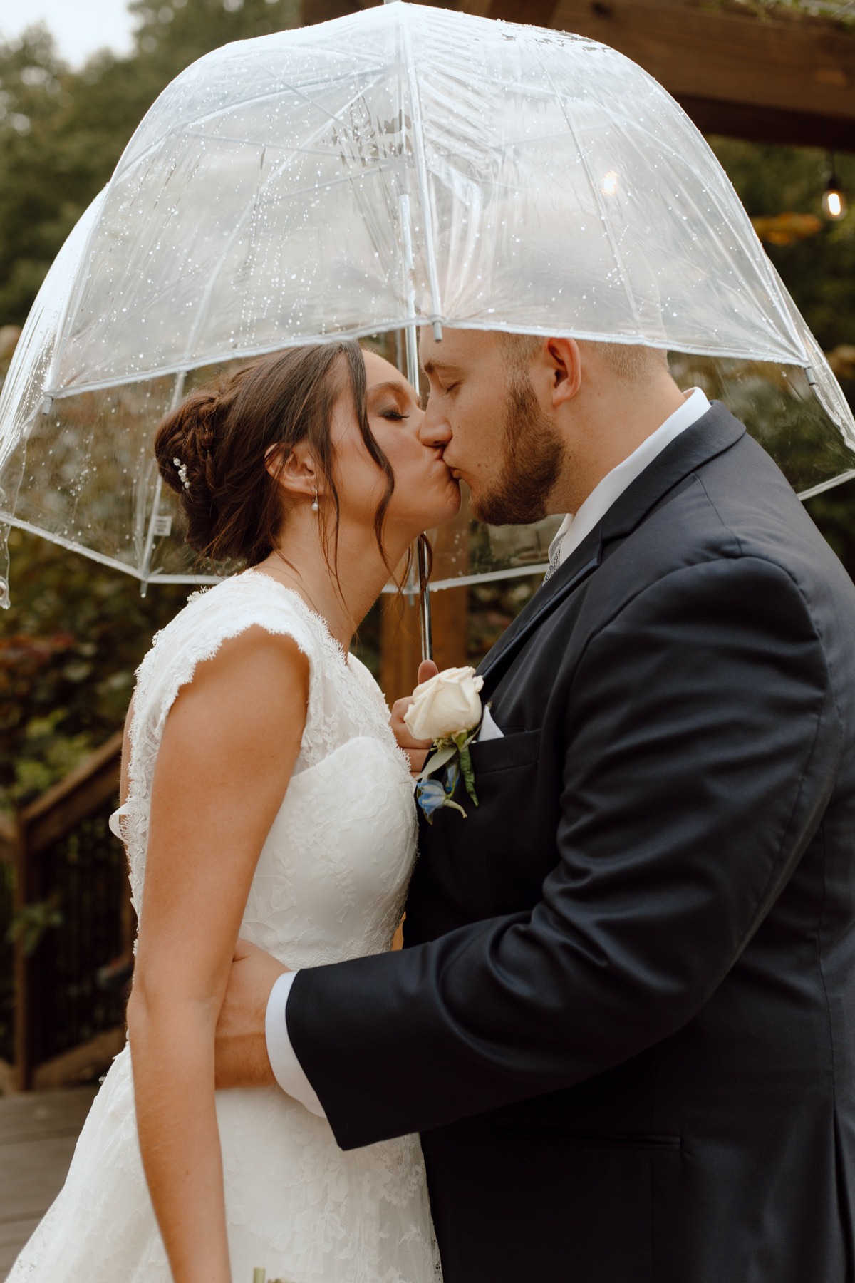 Mariah and Brad, photographed by Winchester, KY husband and wife team A Pair of Perry's Photography, share a romantic kiss under a clear umbrella during their September fall wedding at the picturesque Valley Oaks Wedding Barn in Jeffersonville, Kentucky.